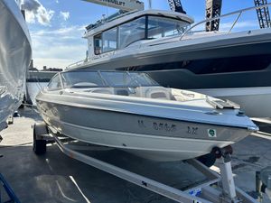 Stingray 195 FX 2005 Stingray 195 FX boat on trailer, docked beside larger vessel under clear sky.
