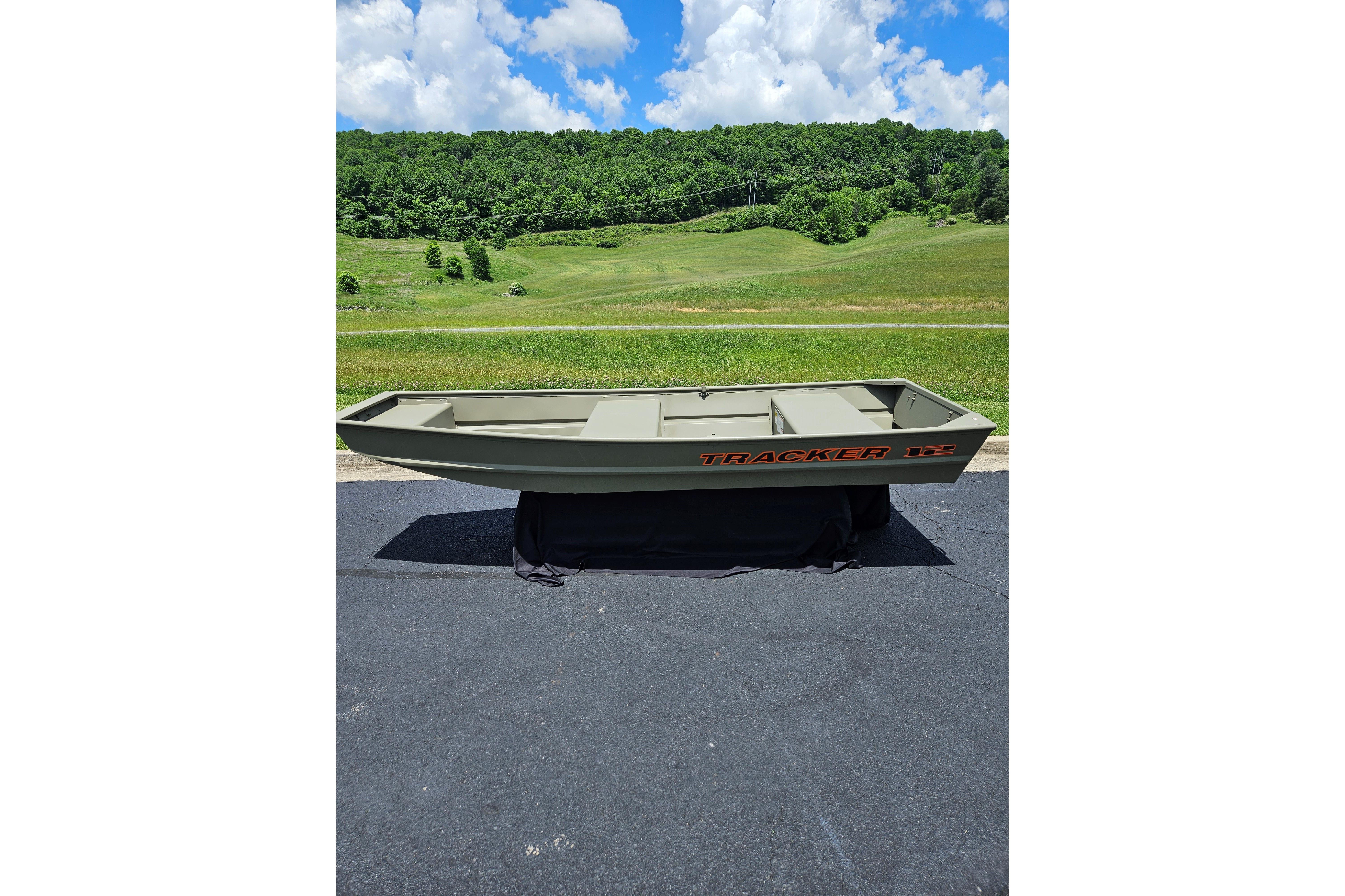Tracker Grizzly 12 Jon 2026 Tracker Grizzly 12 Jon boat on pavement with scenic green hills background.