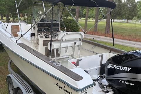 Aquasport 222 1977 Aquasport 222 boat with Mercury FourStroke engine, parked on a trailer in a wooded area.