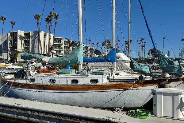 Baba Cutter Vintage 1978 Baba Cutter sailboat docked in marina with palm trees and buildings in background.