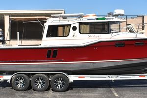 Ranger Tugs R-27 2024 Ranger Tugs R-27 boat on trailer, red and white exterior, parked outdoors.