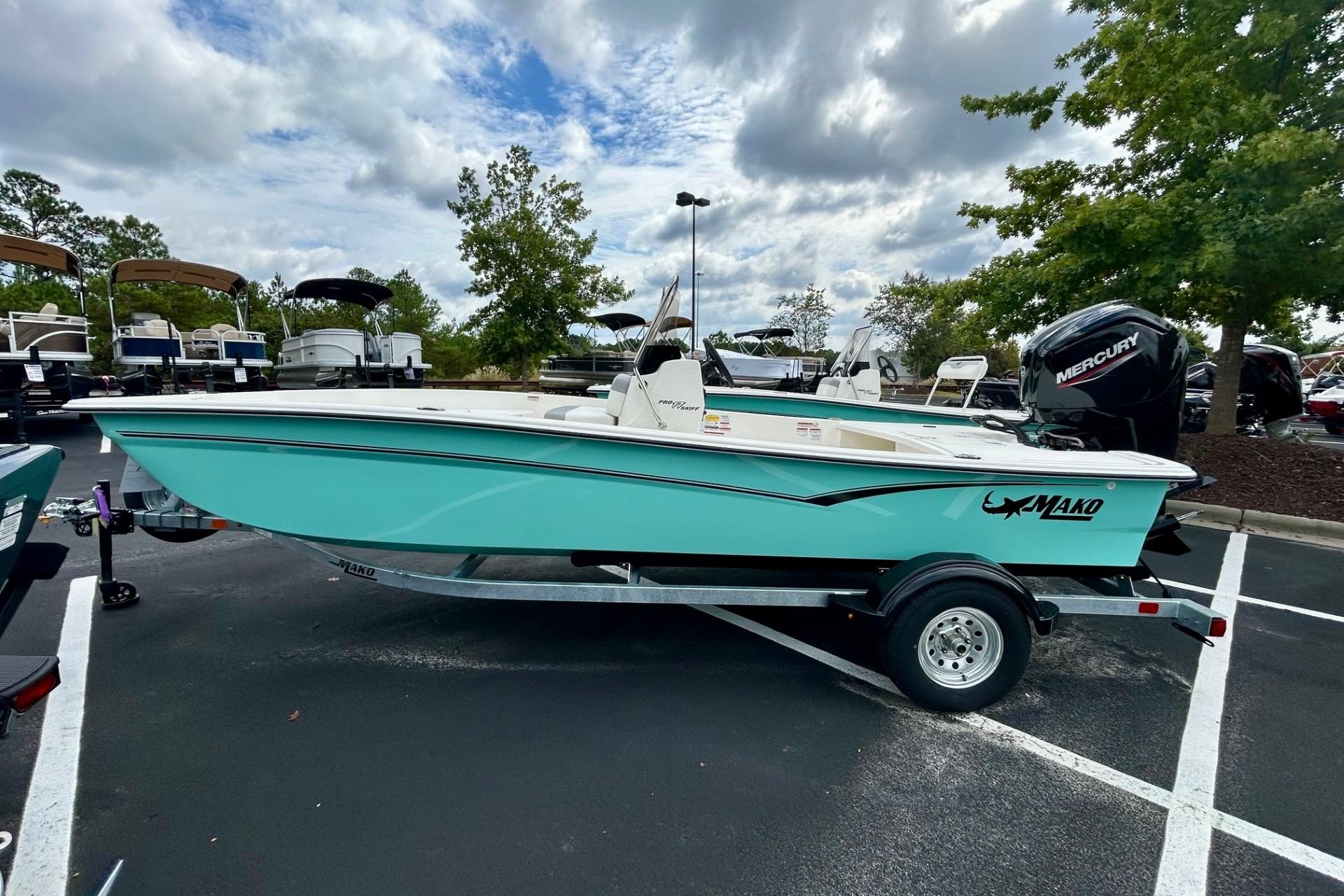 Mako Pro Skiff 17 CC 2026 Mako Pro Skiff 17 CC boat on trailer in parking lot, under cloudy sky.