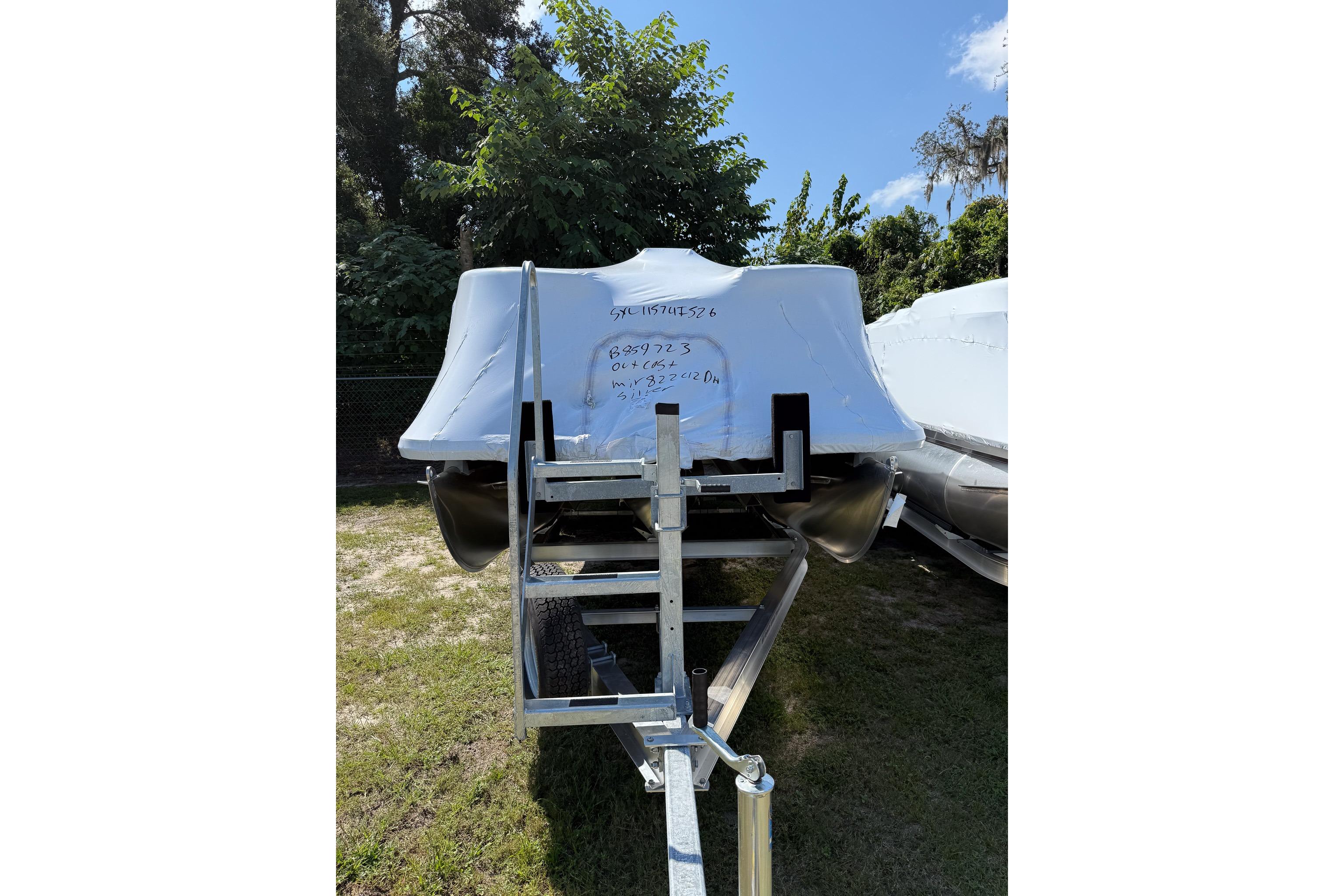 Sylvan MIRAGE 822 CLZ DH 2026 Sylvan MIRAGE 822 CLZ DH boat covered on trailer, surrounded by trees.