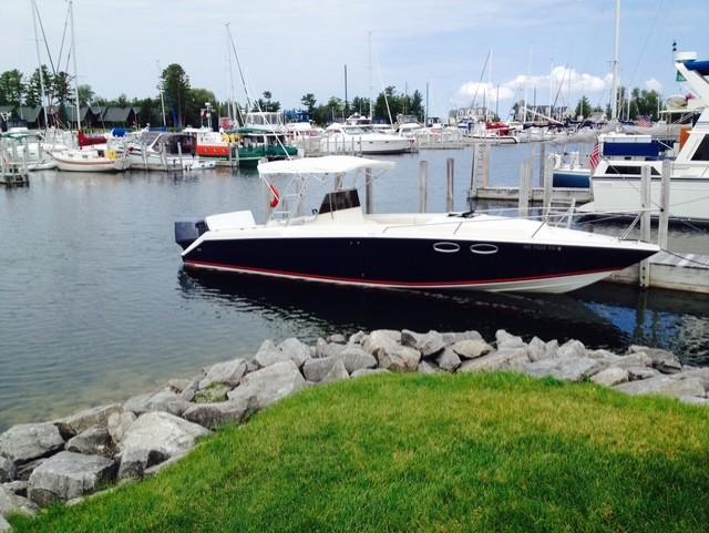 Donzi F-33 1990 Donzi F-33 boat docked in a marina, surrounded by other boats and calm water.