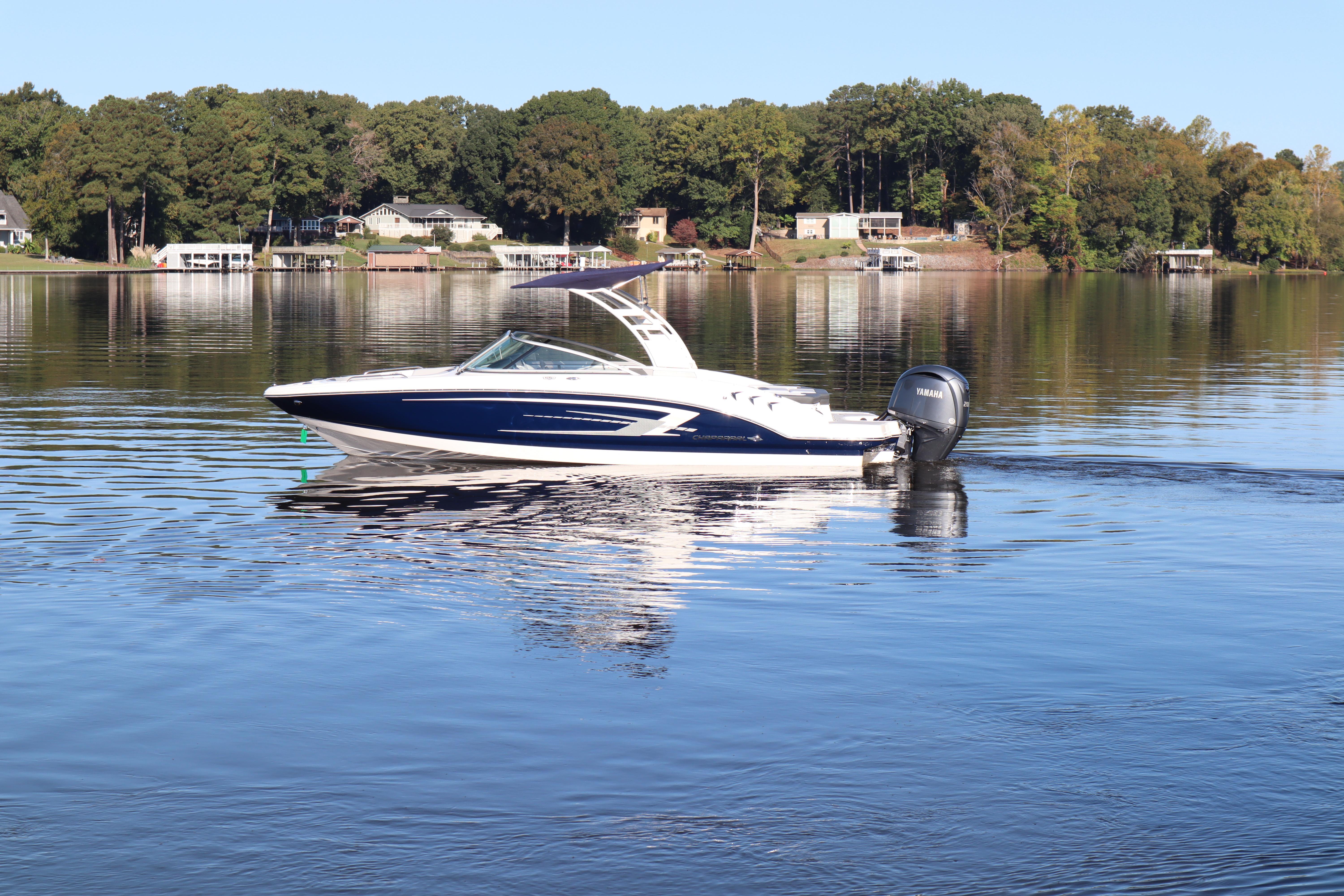 Chaparral 23 SSi OB 2024 Chaparral 23 SSi OB boat cruising on a serene lake with wooded shoreline.