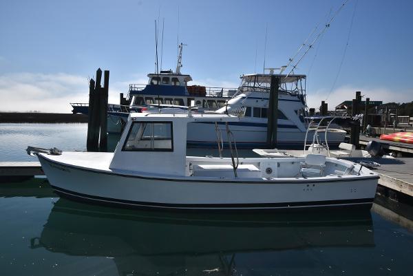 Custom Carolina Built Custom 2011 Downeast boat docked in a marina, with larger vessels in the background.
