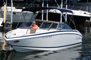 Cobalt 232 2011 Cobalt 232 boat with canopy, docked in marina, man seated at helm.