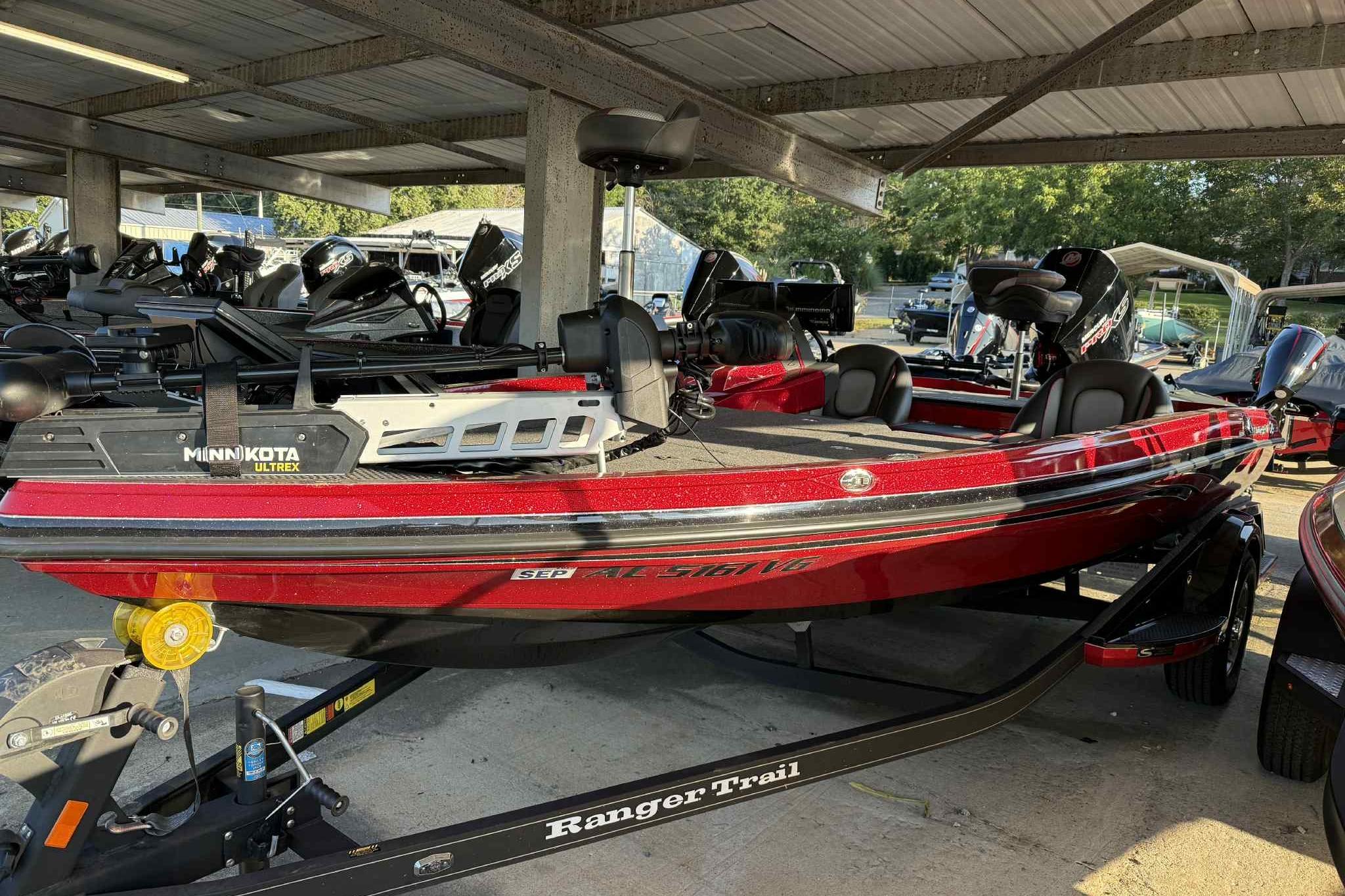 Ranger Z518 2024 Ranger Z518 boat in red, parked under a shelter with Minn Kota Ultrex motor.