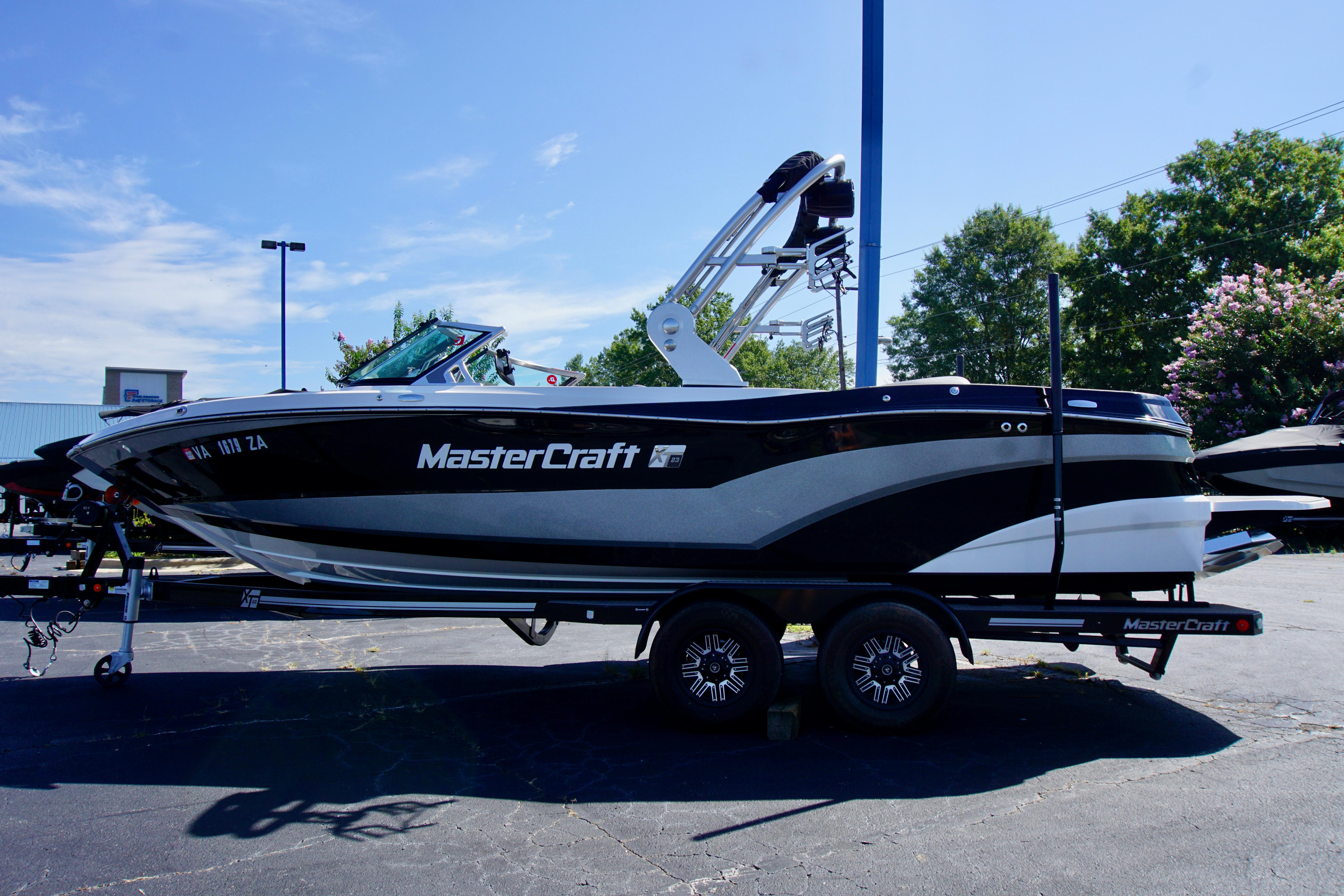 MasterCraft XT23 2019 MasterCraft XT23 boat on trailer, parked outdoors under clear blue sky.