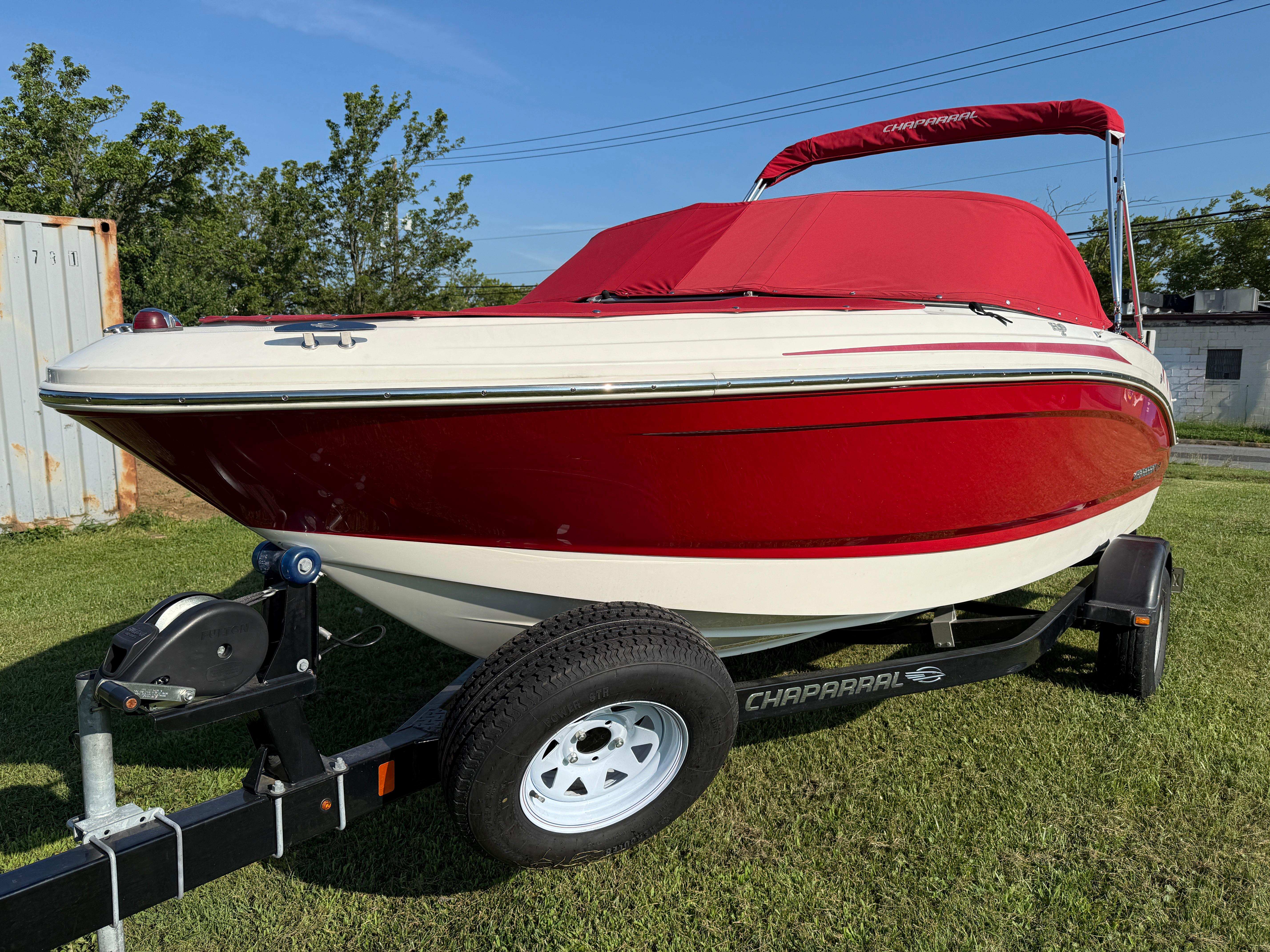 Chaparral 18 H2O Sport 2015 Chaparral 18 H2O Sport boat with red cover on trailer, parked on grass.