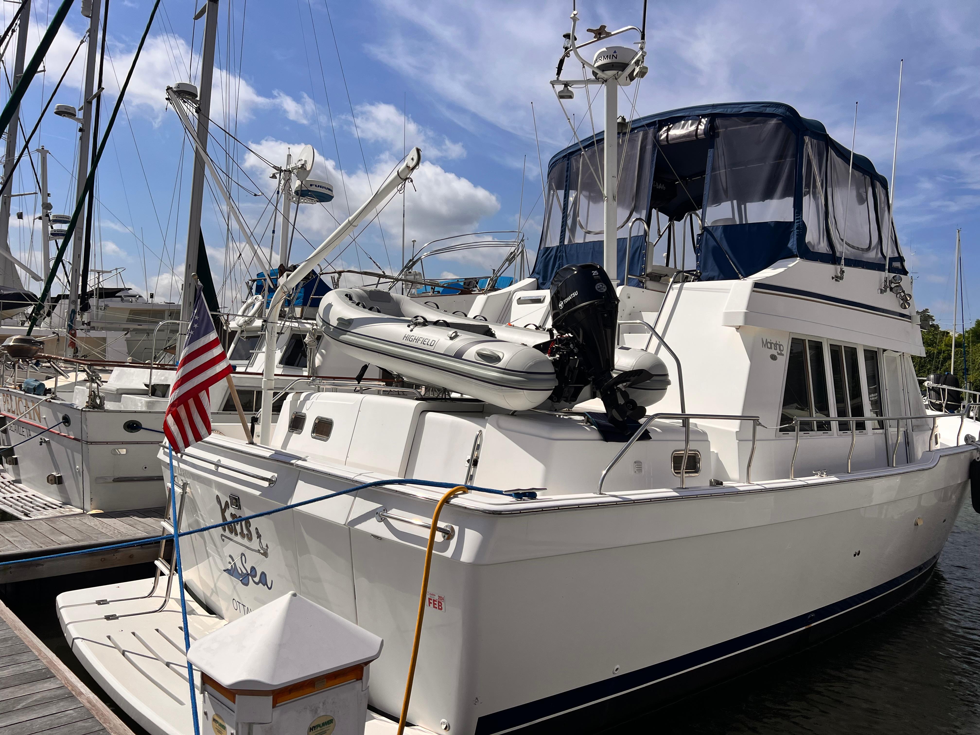 Mainship 430 Trawler 2002 Mainship 430 Trawler docked, featuring a dinghy and American flag, under a blue sky.