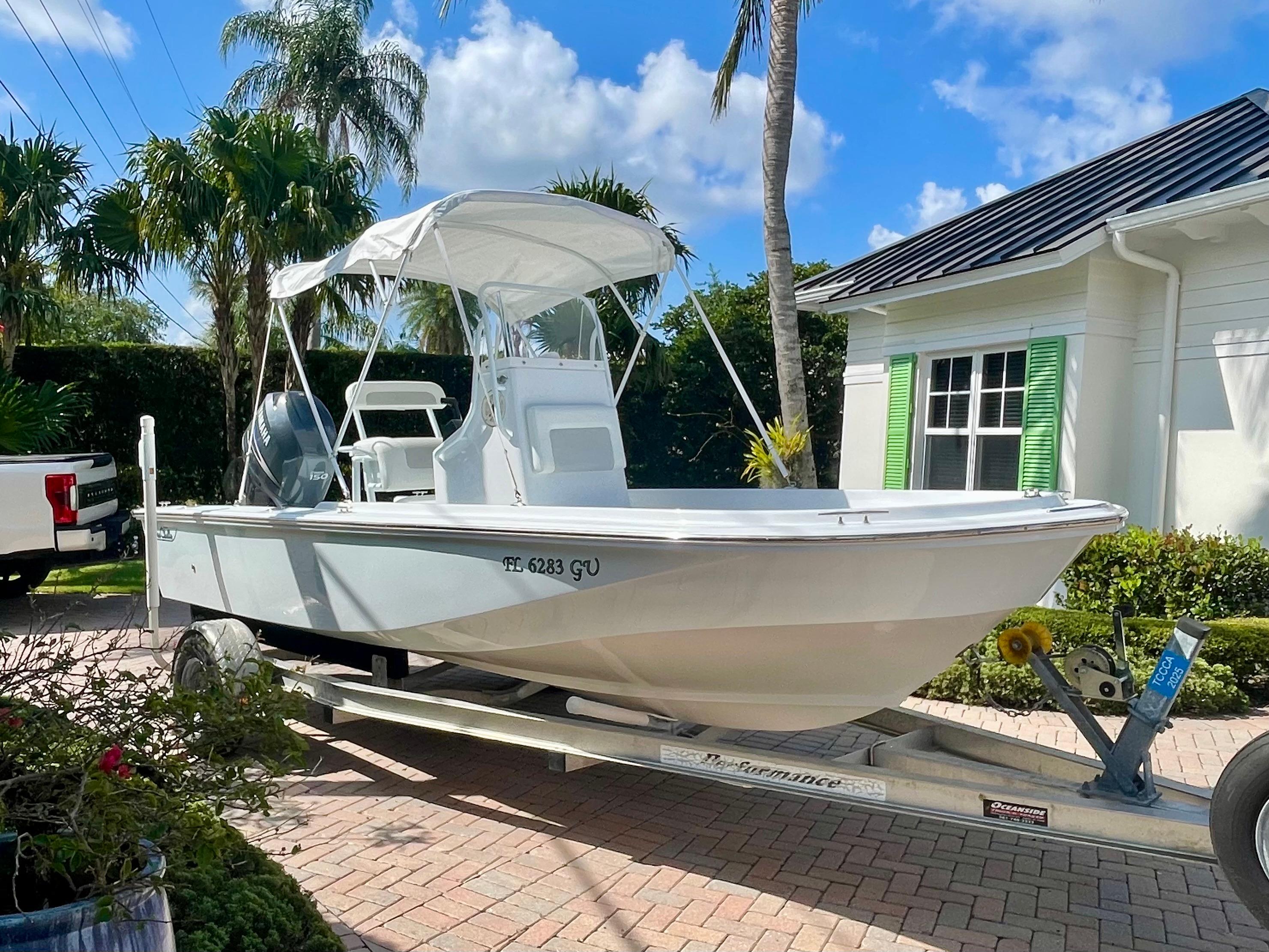 Boston Whaler Custom 1989 Boston Whaler OUTRAGE boat on trailer, parked in sunny driveway with palm trees.