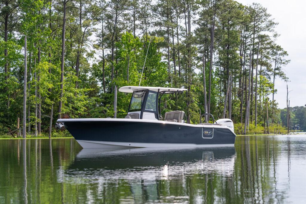 Sea Hunt Ultra 255 SE 2026 Sea Hunt Ultra 255 SE boat on calm lake with forest backdrop.