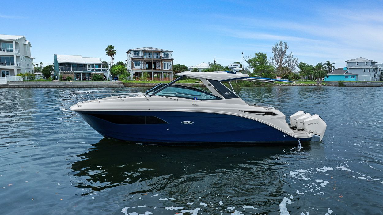 Sea Ray Sundancer 320 Outboard 2021 Sea Ray Sundancer 320 Outboard on calm water, with waterfront homes in the background.