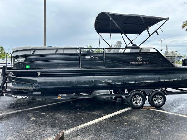 Regency 230 LE3 Sport 2023 Regency 230 LE3 Sport pontoon boat on a trailer in a parking lot.
