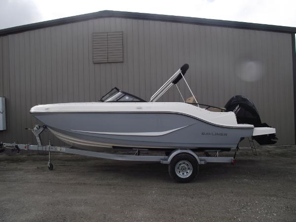 Bayliner D20 2025 Bayliner D20 boat on trailer, parked outside a warehouse.