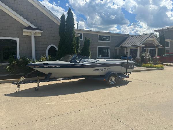 MasterCraft ProStar 190 1989 MasterCraft ProStar 190 boat on trailer, parked outside a building under a cloudy sky.