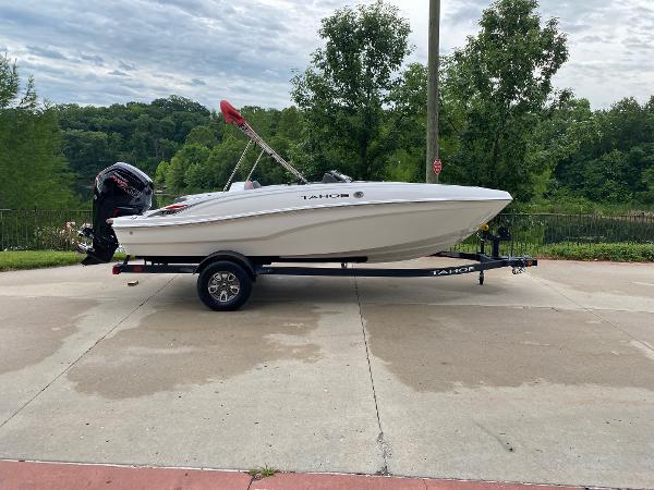 Tahoe T18 2025 Tahoe T18 boat on trailer, parked outdoors with lush greenery background.