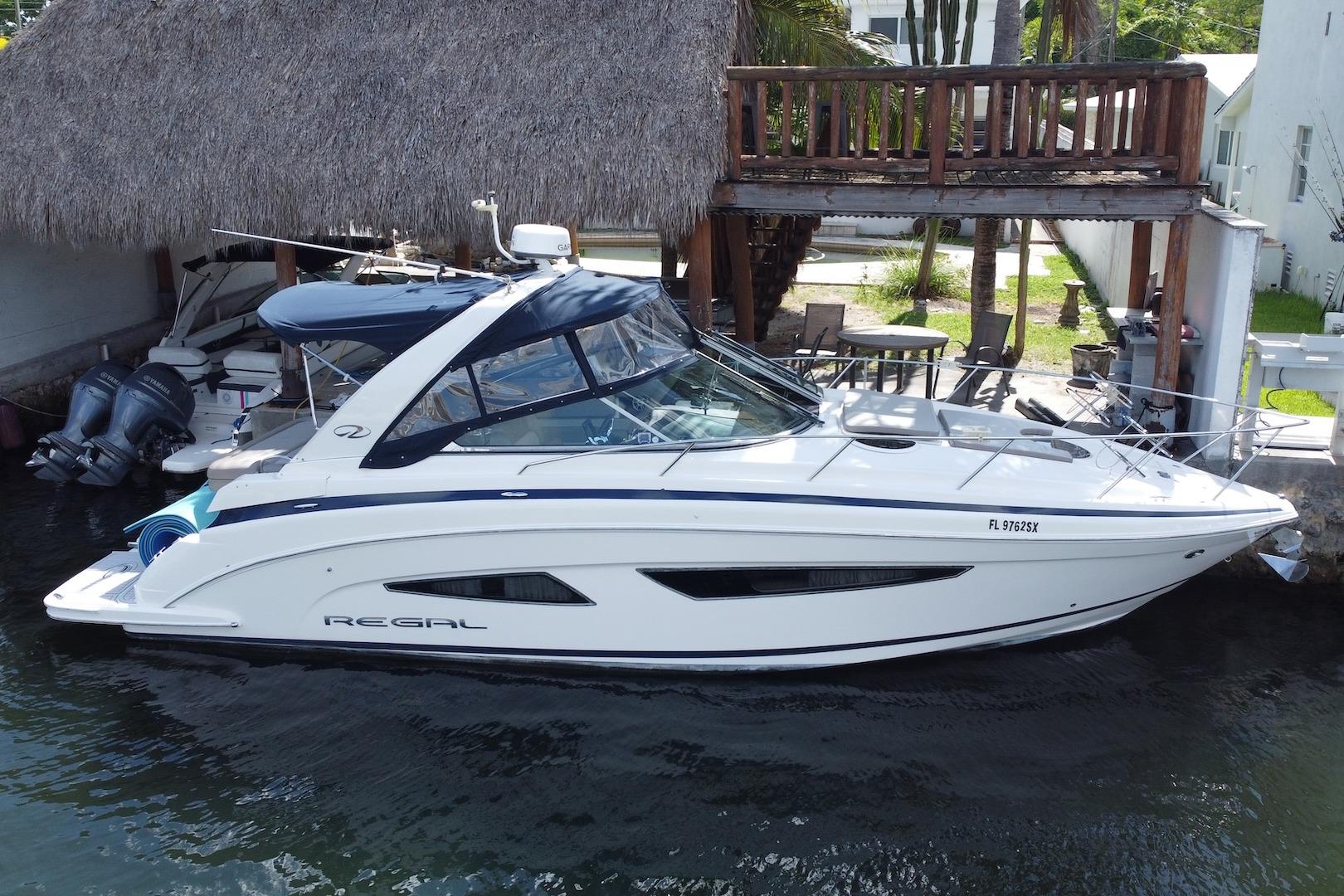 Regal 32 Express 2015 Regal 32 Express boat docked by a thatched-roof structure.