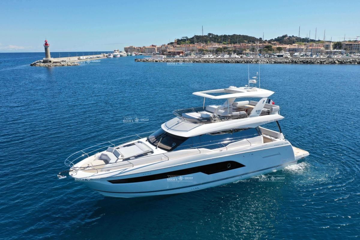 Prestige 630 Fly Luxury 2020 Prestige 630 Fly yacht cruising near a scenic coastal lighthouse.