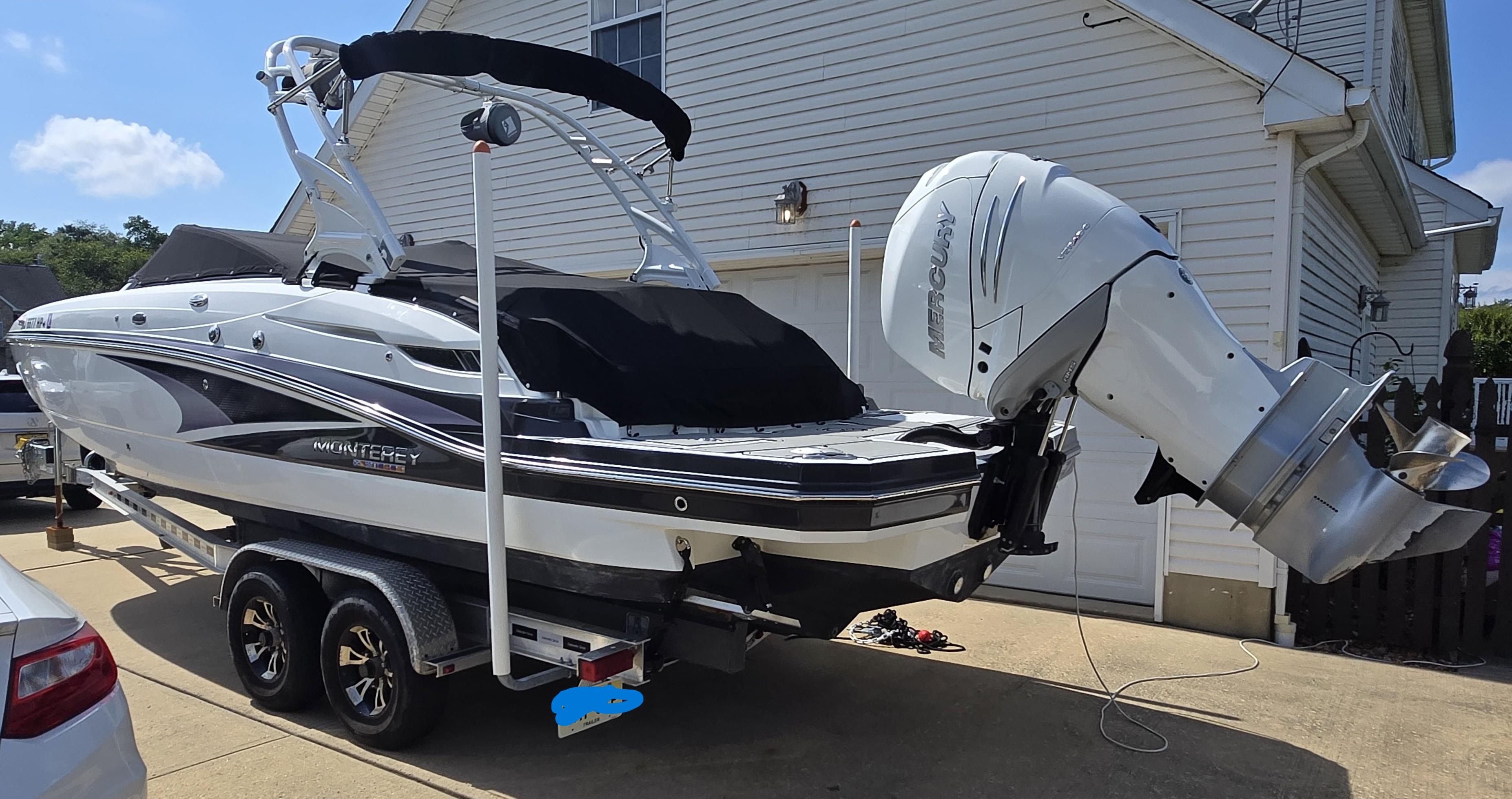 Monterey M-65 2021 Monterey M-65 boat on trailer, parked in driveway, with Mercury outboard motor.