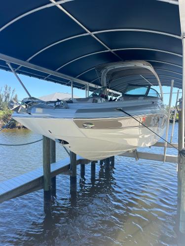 Crownline 280 XSS 2020 Crownline 280 XSS boat docked under a blue canopy on a sunny day.