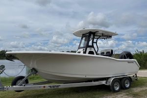 Tidewater 232 CC Adventure 2026 Tidewater 232 CC Adventure boat on trailer by a lake under cloudy sky.