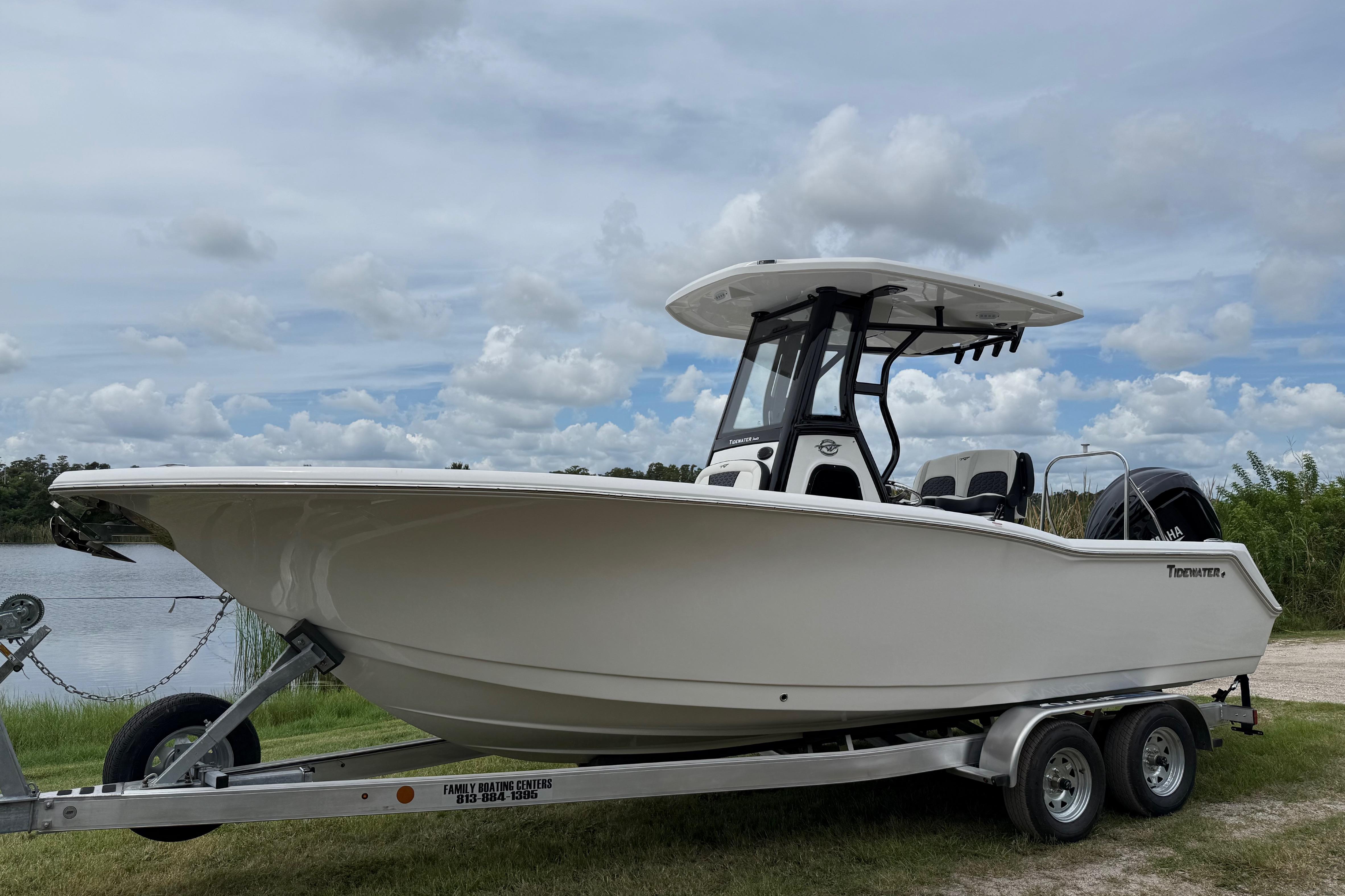 Tidewater 232 CC Adventure 2026 Tidewater 232 CC Adventure boat on trailer by a lake under cloudy sky.