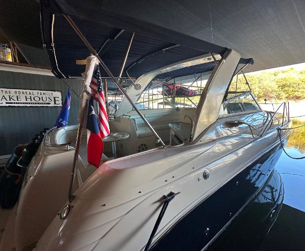 Rinker Fiesta Vee 312 2003 Rinker Fiesta Vee 312 boat docked at a lake house with flags displayed.