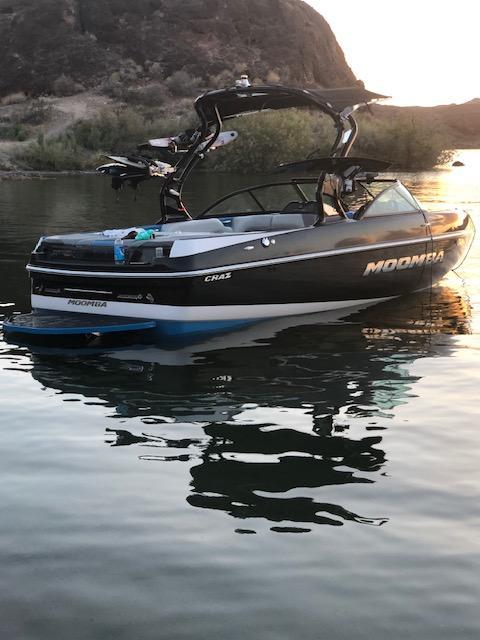 Moomba c 2016 Moomba Craz boat on calm water at sunset, with rocky landscape background.