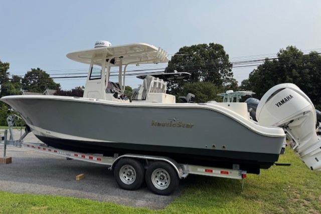 NauticStar 28 XS 2023 NauticStar 28 XS boat on trailer with Yamaha engine, parked on grass.