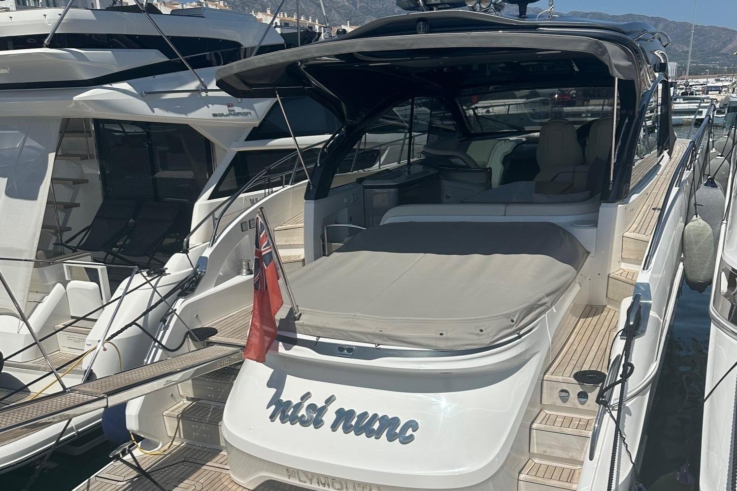 Princess V50 Open 2023 Princess V50 Open yacht docked in marina, rear view with flag.