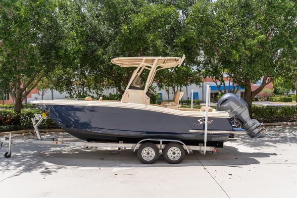 Scout 215 XSF 2023 Scout 215 XSF boat on trailer, parked outdoors under trees.