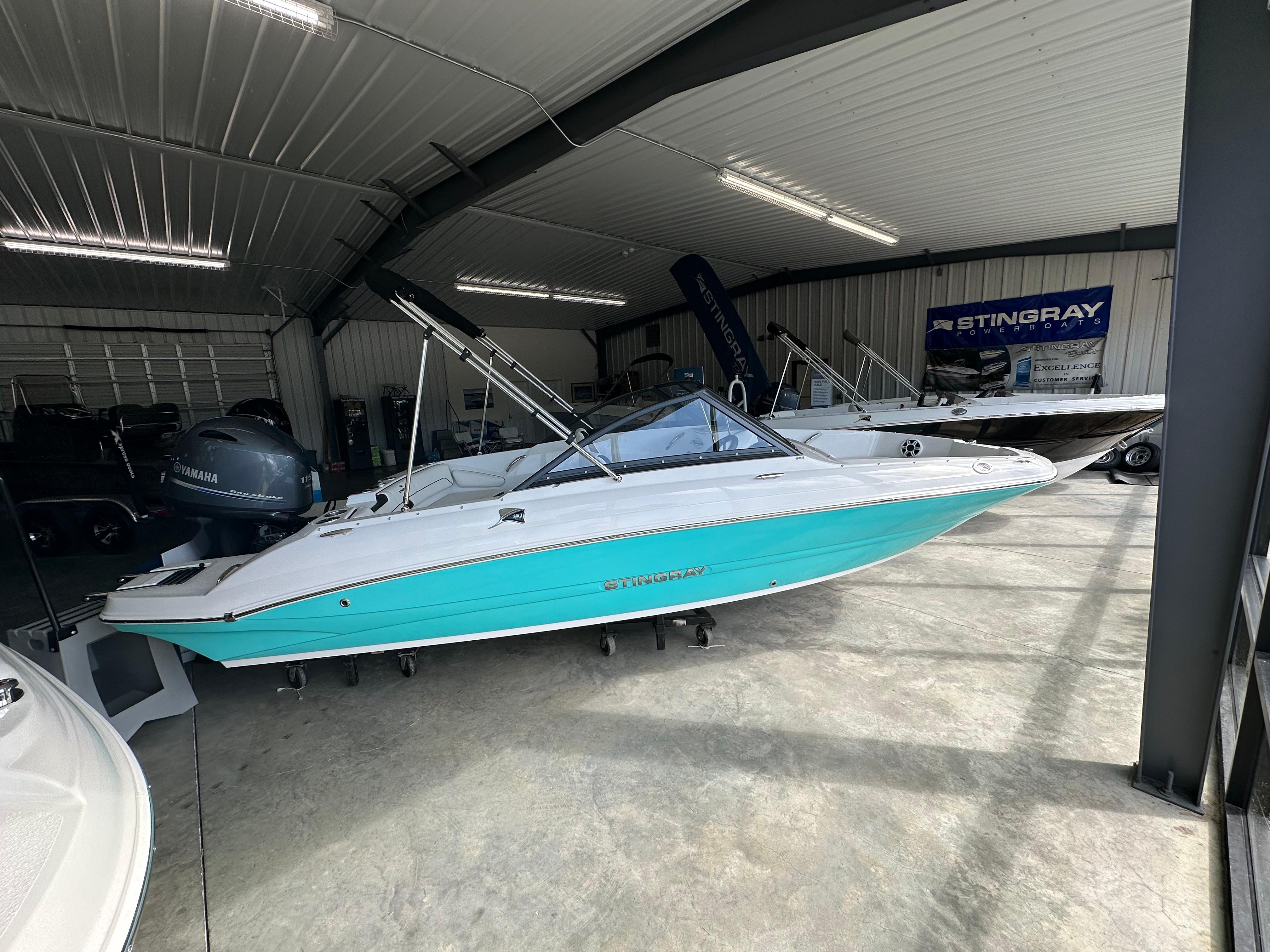 Stingray 191 DC 2026 Stingray 191 DC boat in showroom, turquoise and white design, under bright lighting.