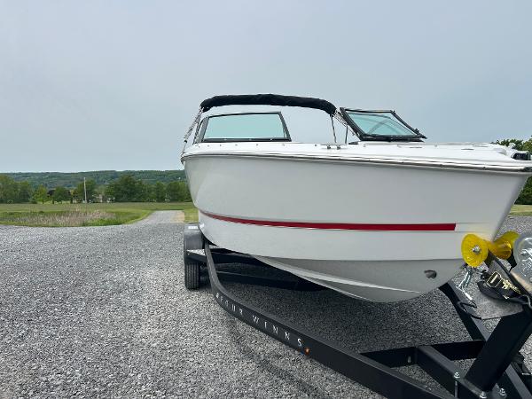 Four Winns H2 Freedom 2025 Four Winns H2 Freedom boat on trailer, parked on gravel with scenic background.