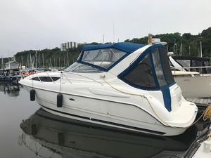 Bayliner 305 2005 Bayliner 305 boat docked in marina, featuring blue canopy and sleek white design.