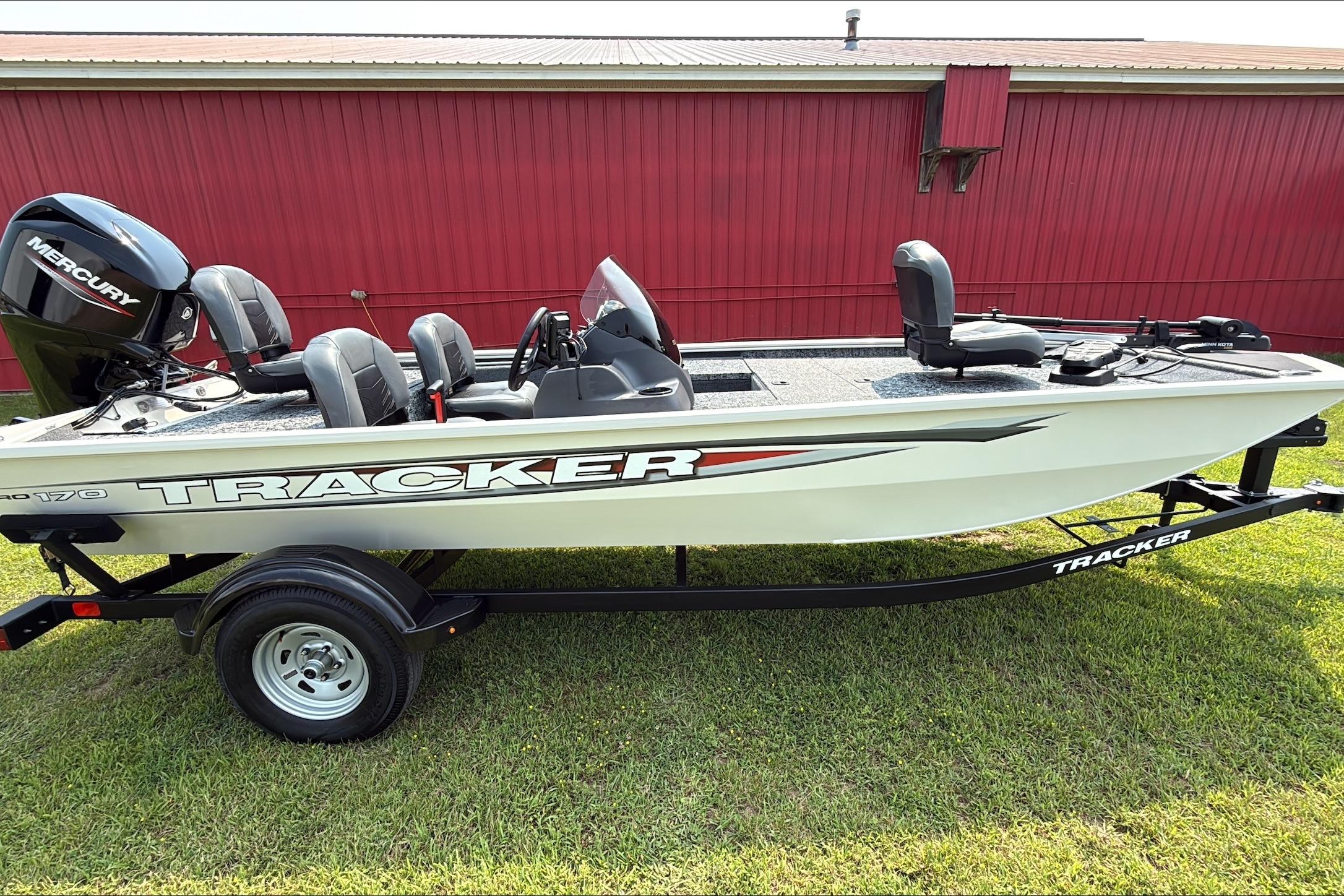 Tracker Pro 170 2026 Tracker Pro 170 boat on trailer, parked on grass, with red building background.