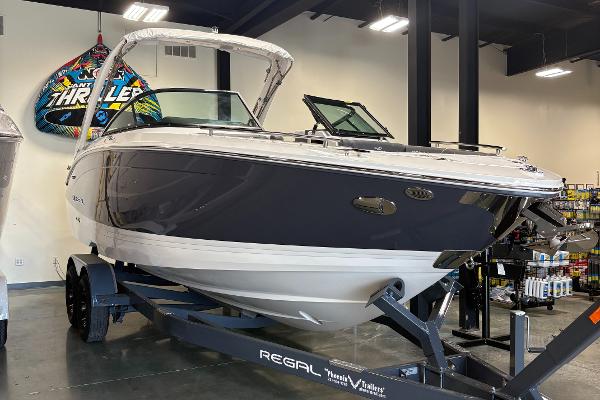 Regal LS6 2025 Regal LS6 boat on trailer in showroom, featuring sleek design and modern features.