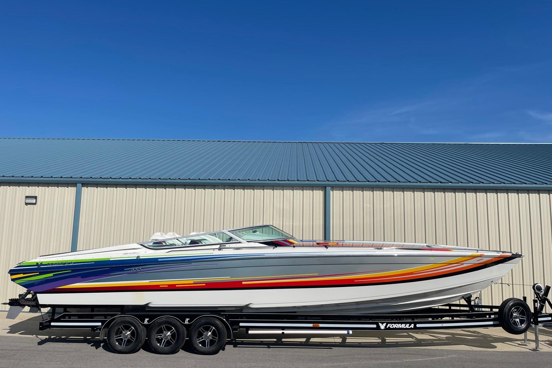 Formula 382 FASTech 2004 Formula 382 FASTech boat on trailer, vibrant design, parked by metal building.