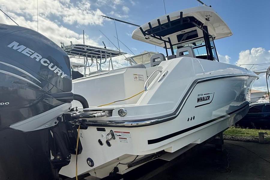 Boston Whaler 330 Outrage 2023 Boston Whaler 330 Outrage boat with Mercury engine, docked under a blue sky.