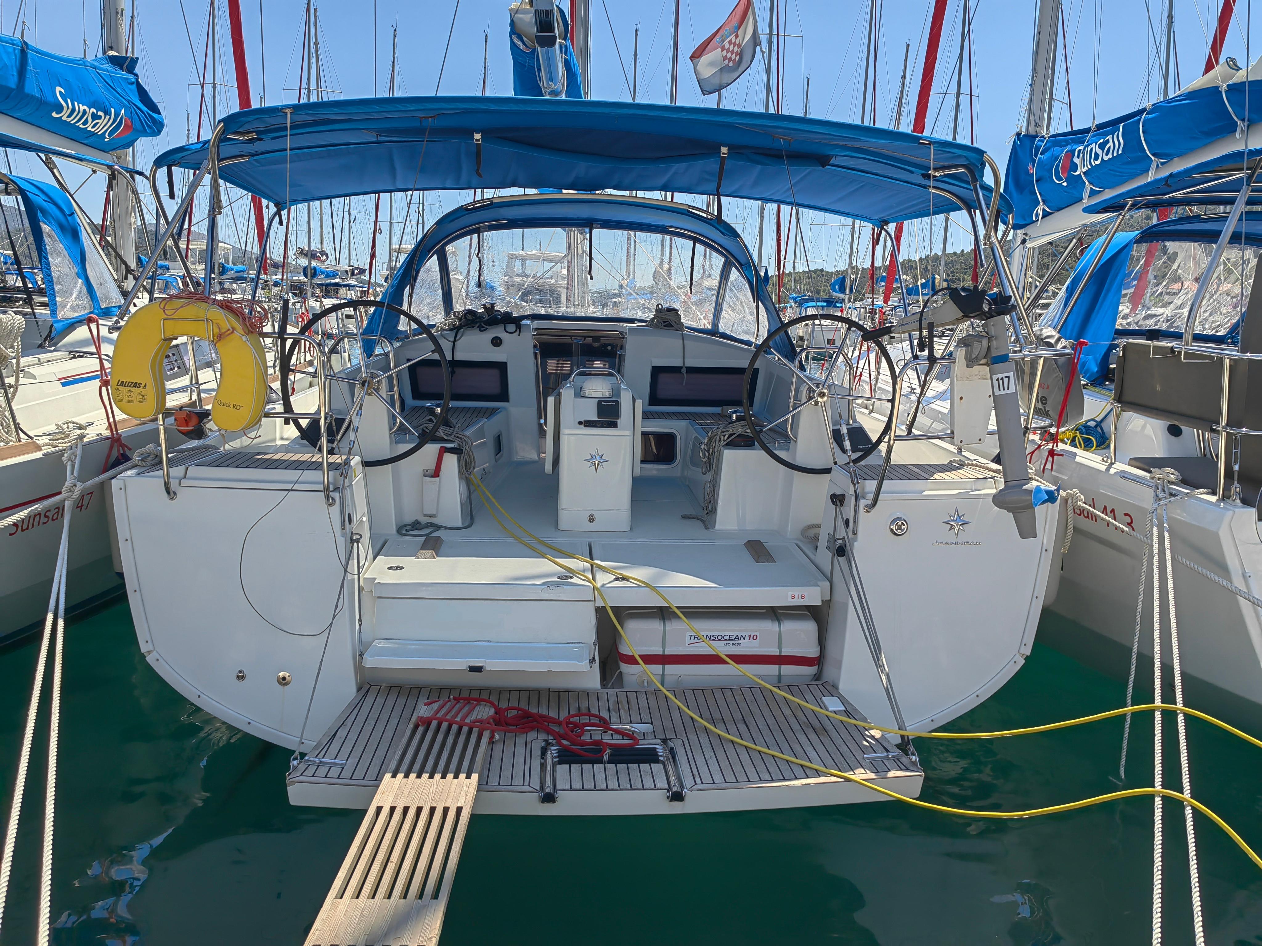 Jeanneau Sun Odyssey 440 2019 Jeanneau Sun Odyssey 440 sailboat docked, featuring dual steering wheels and blue canopy.