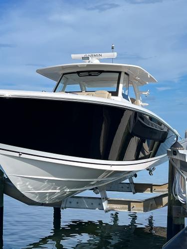 Pursuit S 408 Sport 2019 Pursuit S 408 Sport boat docked on a lift, under a clear blue sky.