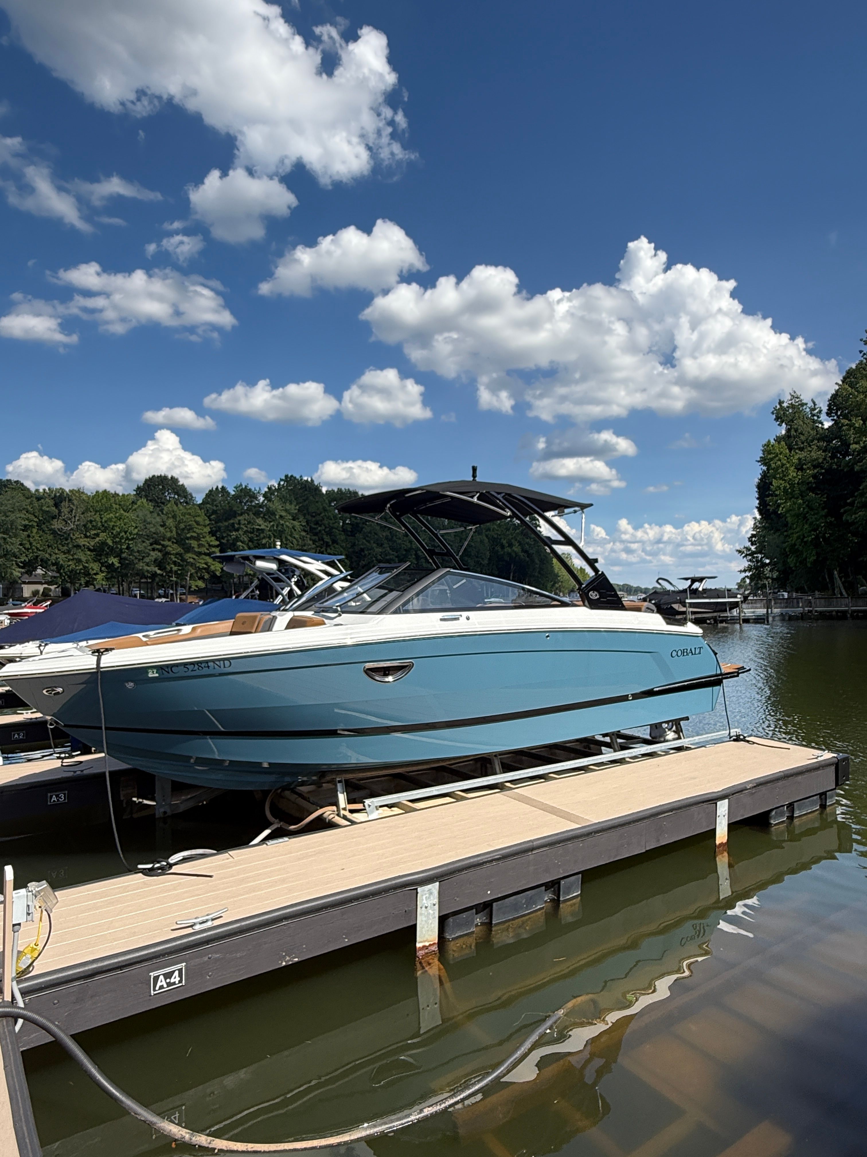 Cobalt R6 2024 Cobalt R6 boat docked on a sunny day with blue skies and clouds.