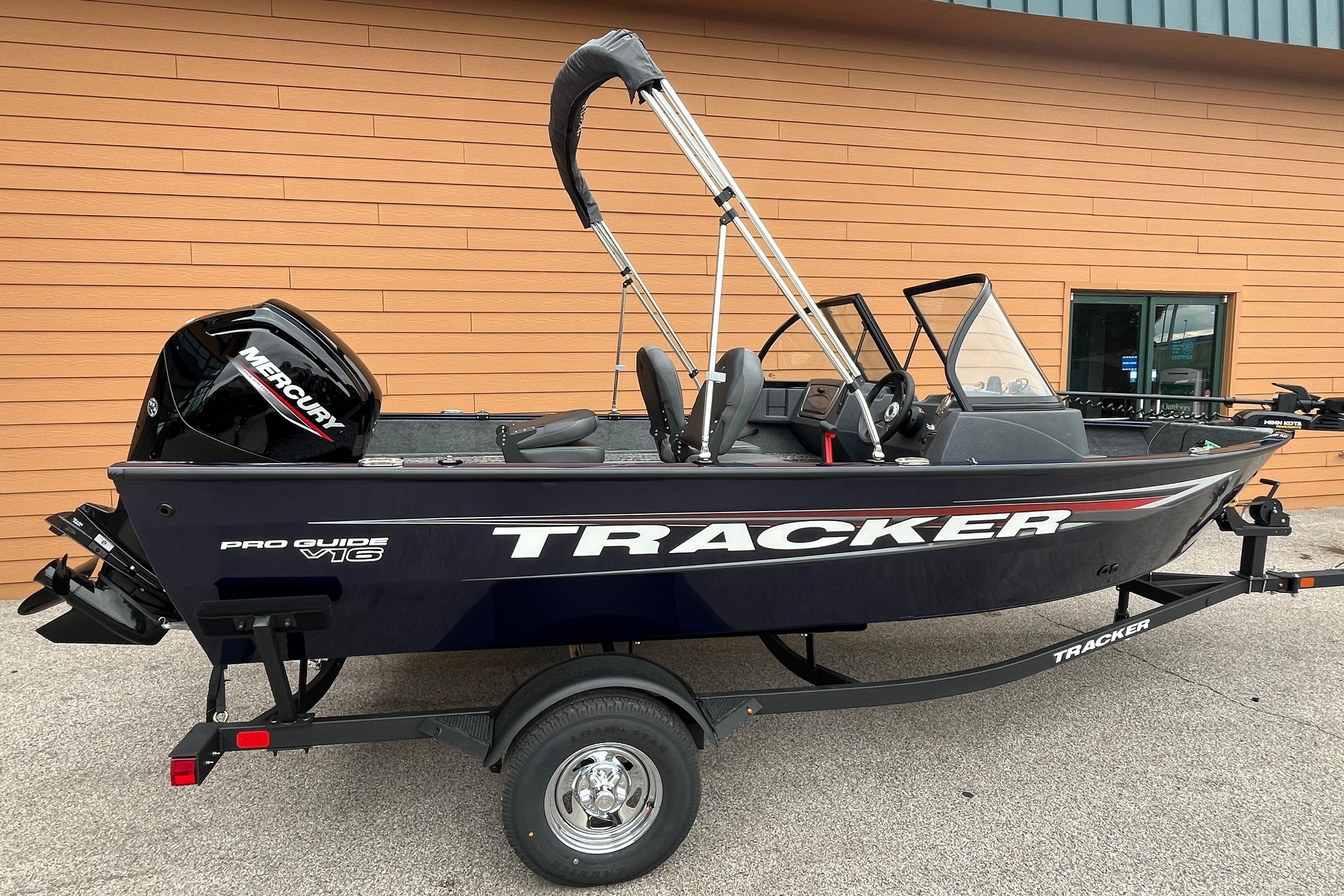 Tracker Pro Guide V-16 WT 2026 Tracker Pro Guide V-16 WT boat on trailer, parked by a building.