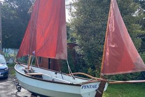Drascombe Dabber 1990 Drascombe Dabber sailboat with red sails on a trailer, named "Pintail."