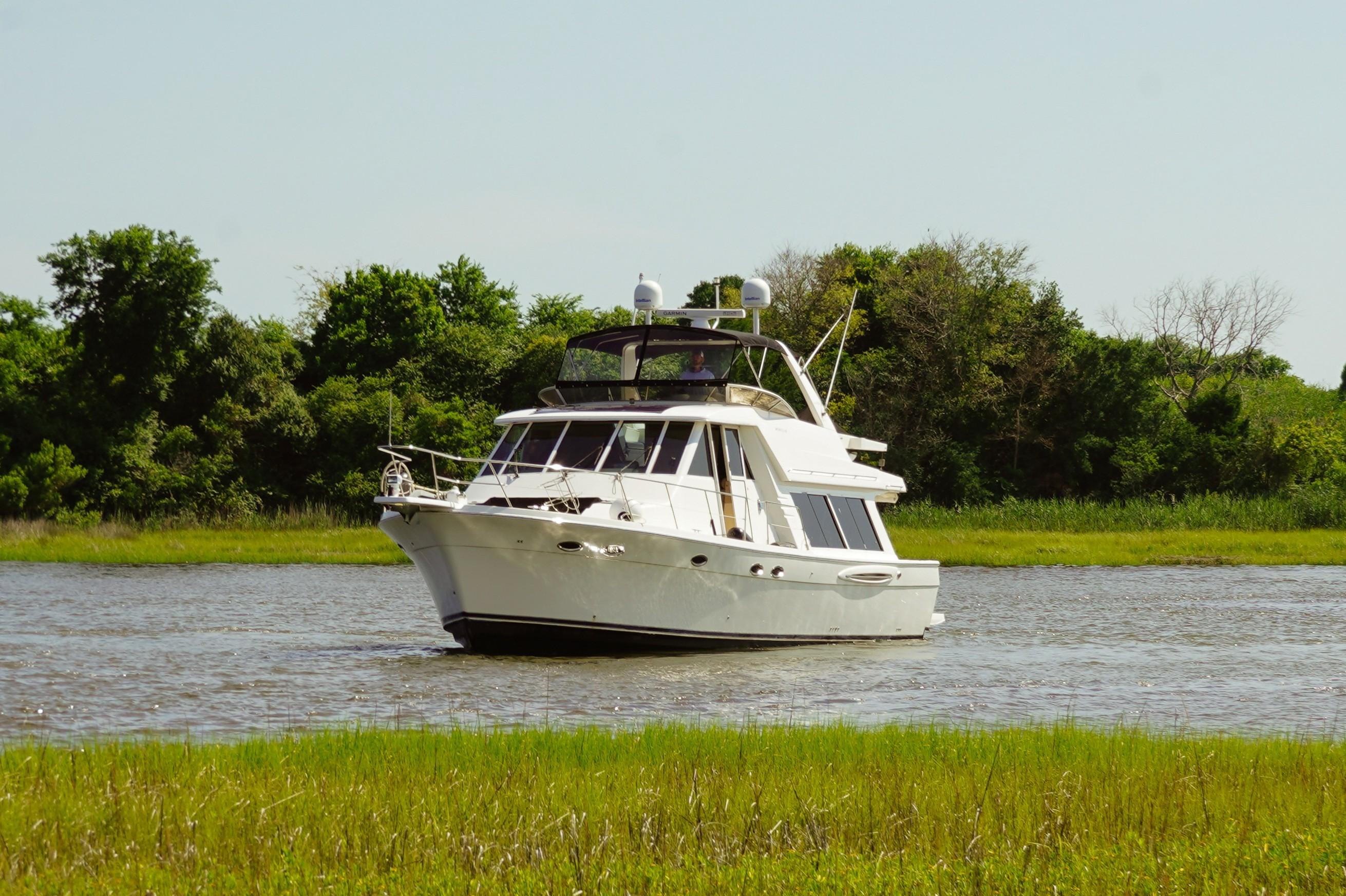 Meridian 490 Pilothouse 2008 Meridian 490 Pilothouse yacht cruising on a serene river with lush greenery.