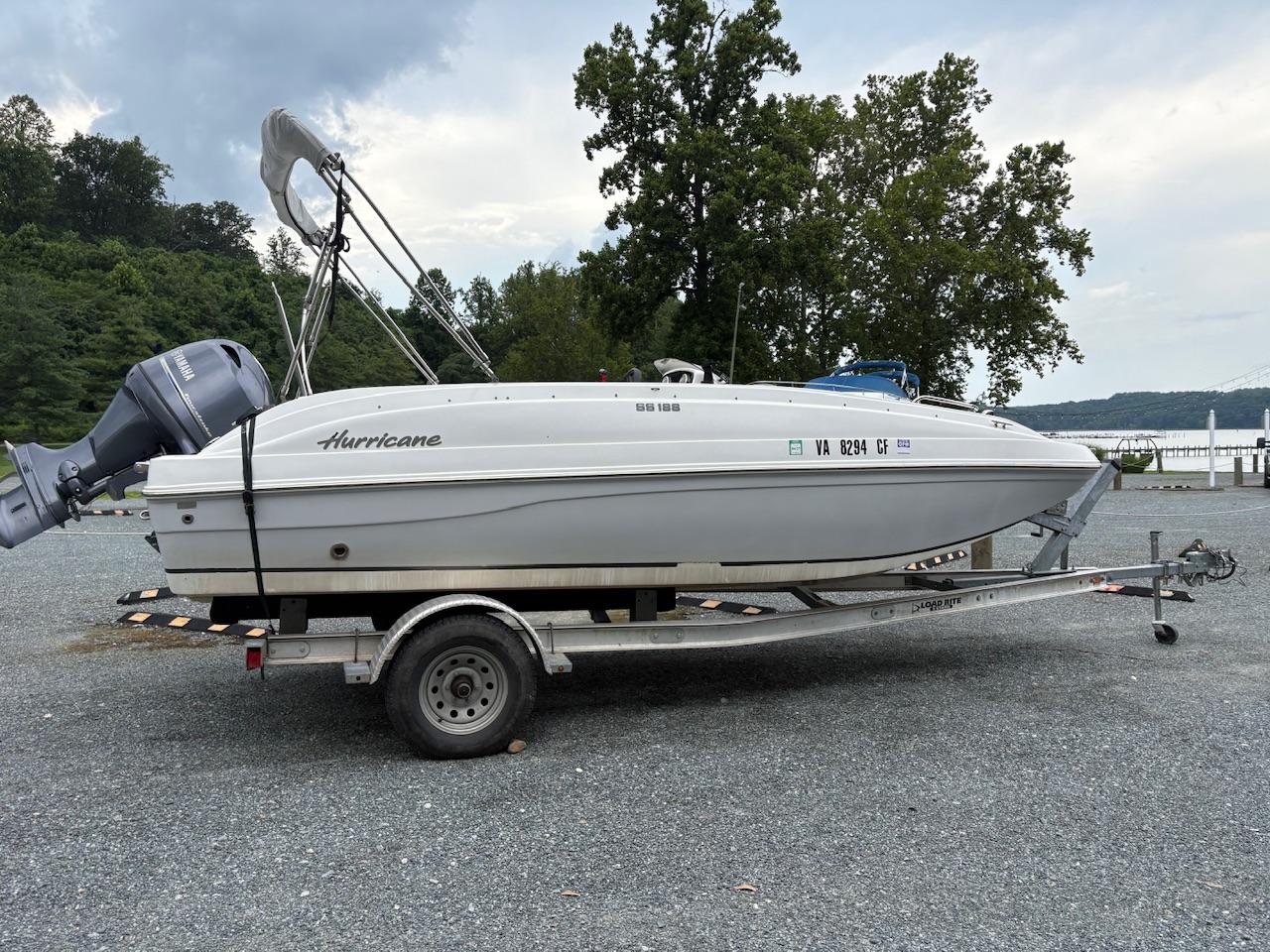Hurricane 188 2016 Hurricane 188 boat on trailer, parked near a lake with trees in the background.