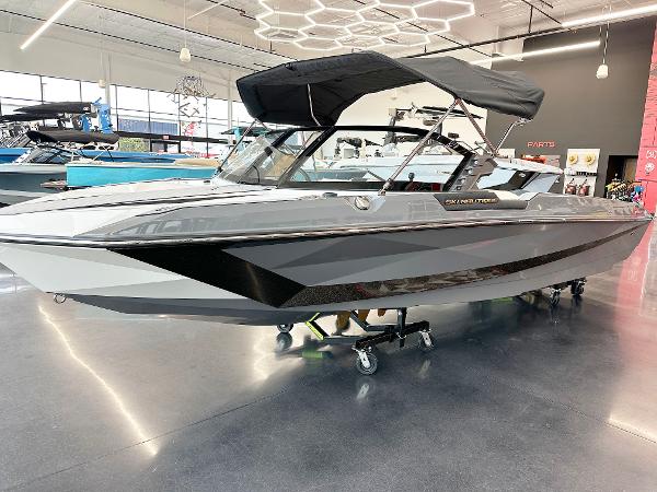 Nautique Ski Nautique 2025 Nautique Ski boat in showroom, sleek design, black canopy, modern interior.