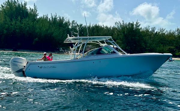 Sailfish 325 DC 2017 Sailfish 325 DC boat cruising on water near a forested shoreline.