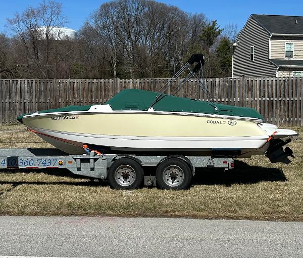 Cobalt 210 WSS 2012 Cobalt 210 WSS boat on trailer, green cover, parked on grass.